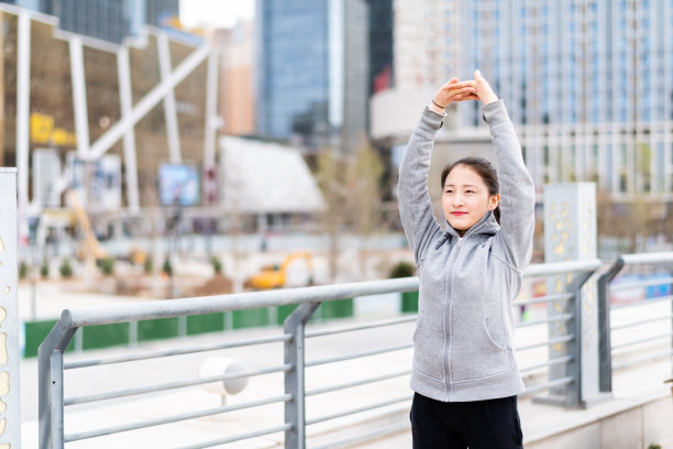 亚洲年轻女子站和伸展后，在城市跑步图片下载