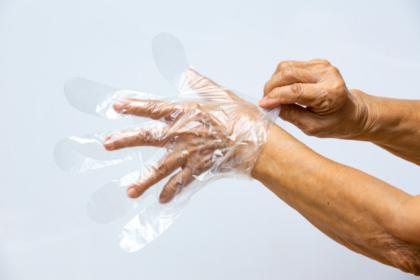 灰色背景，老妇手戴一次性塑料防护手套，特写，预防新冠肺炎，冠状病毒，细菌，医疗保健图片下载