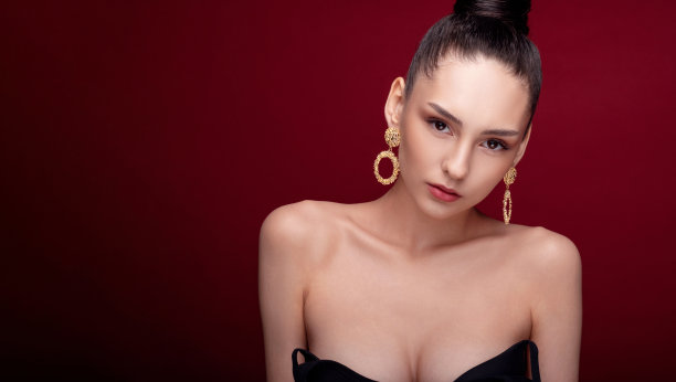 特写美女肖像时尚模特，干净的皮肤，红色的背景，金色耳环，发型高发髻，艺术创意时尚摄影图片下载