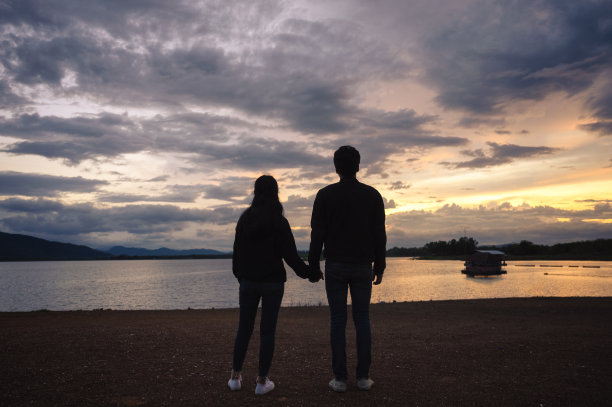日落时分，一对年轻夫妇在水库上牵着手图片下载