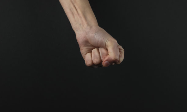 女人拳头手势在黑色背景上素材图片