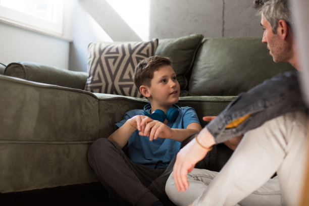 快乐的爸爸和学龄前的儿子一起在沙发上放松图片下载