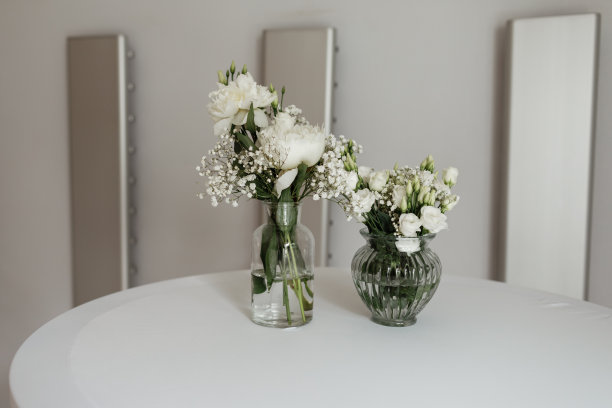 白色的花组成的花瓶在白色的桌子上。有选择性的重点图片下载