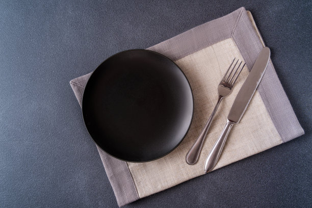 空的黑色盘子在餐巾上的桌面视图，为文本复制空间。图片下载