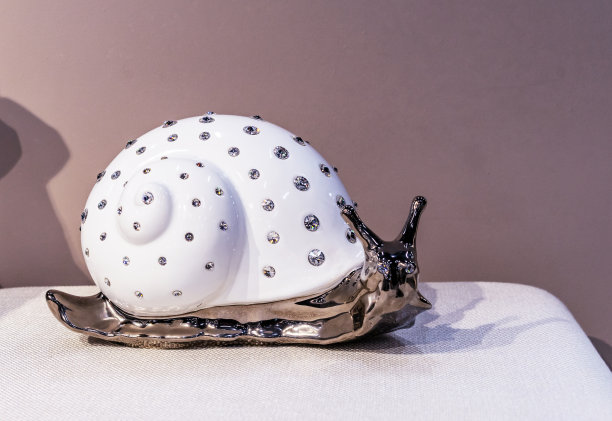 瓷的蜗牛小雕像，一个白色的壳。家居装饰。图片下载