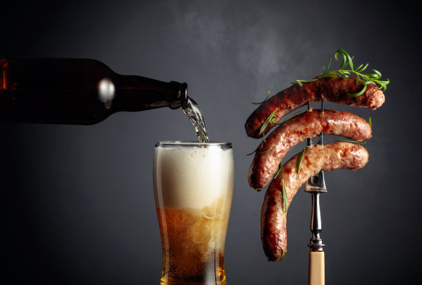啤酒和迷迭香烤巴伐利亚香肠。叉子上撒着迷迭香的香肠。图片下载
