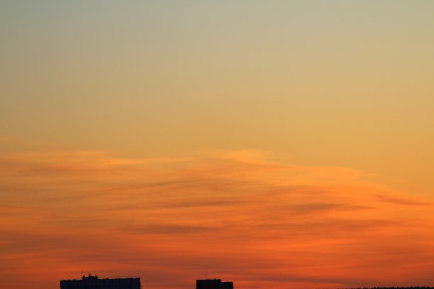 太阳在地平线下，多层城市建筑的屋顶在背景云在火红的橙色天空在日落或黎明由太阳背光。放置文本和设计图片下载