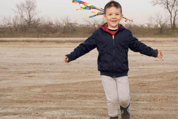 一个4岁的男孩在空旷的海滩上玩耍。放风筝。图片下载