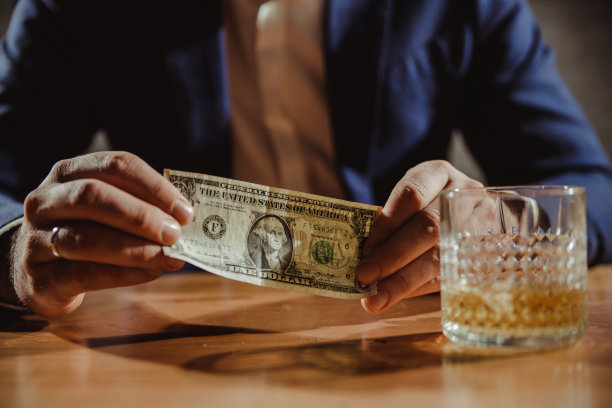 近距离握住钱的手。男人喝威士忌图片下载