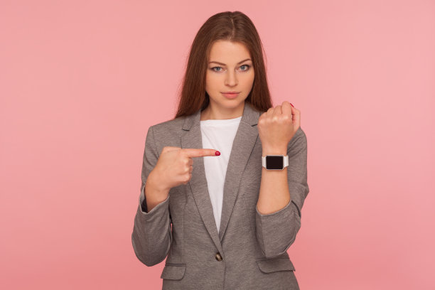 晚了，快点儿!肖像不耐烦的担心忙碌的女士在商务西装指向她的手腕上的手表图片下载