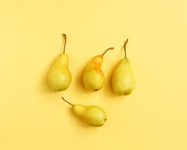 黄色背景上的黄色梨子。梨家居装饰。黄色装饰梨图片下载