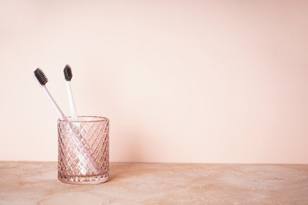 两支牙刷放在一个玻璃上，米色背景上有文字空间图片下载