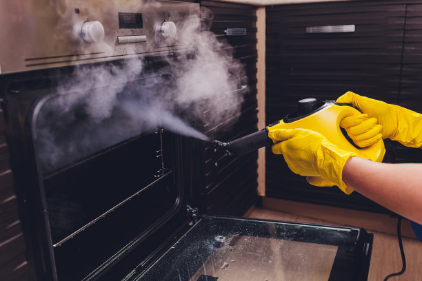 蒸汽清洗烤箱房清洁手特写。图片下载