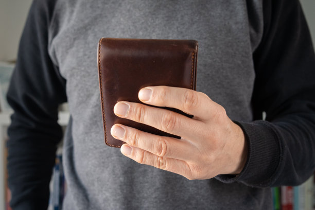 正面近距离观察未知的白人男子在天拿着皮革棕色钱包图片下载