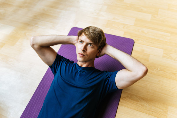 俯视图英俊的白人青年运动员苗条的身体锻炼做坐起来锻炼在瑜伽垫子上健身馆为良好的健康，健美者，锻炼健身，锻炼和运动的概念图片下载