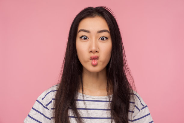 可爱的有趣的女孩的肖像与深色头发显示鱼脸鬼脸噘嘴，胡闹图片下载