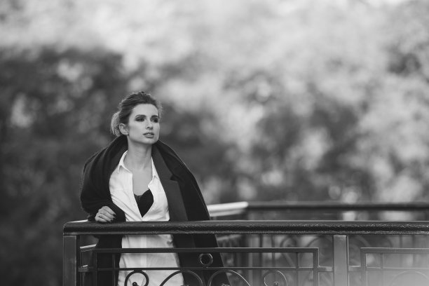 在一个阴冷的日子里，一个美丽的孤独的女人在桥上，她的头发在风中飘动，嘴唇丰满。黑白艺术照片。软选择聚焦。图片下载