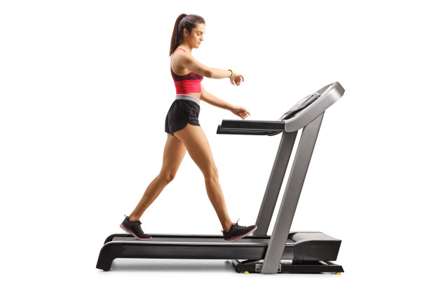 健康的年轻女子在跑步机上锻炼并检查她的臂环图片下载