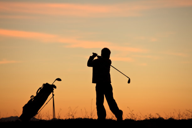 剪影的年轻的少年高尔夫球手做一个秋千图片下载