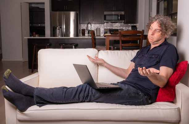 一名男子在城市公寓的家中工作，看起来很恼怒图片下载