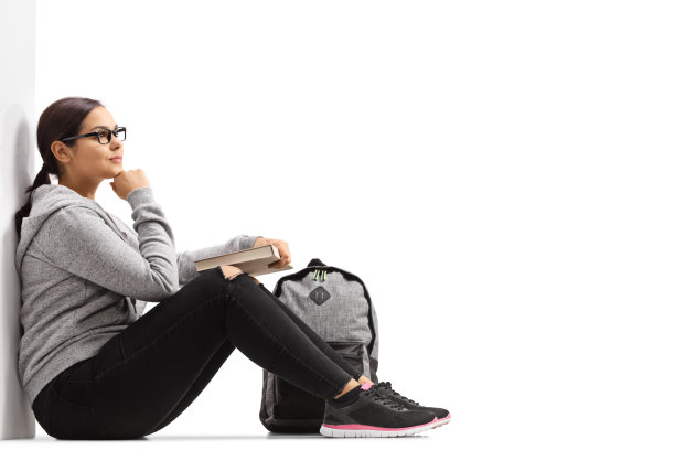 女学生坐在地板上，靠在墙上图片下载