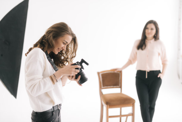 一个年轻美丽的女人的肖像检查图片上的相机屏幕。图片下载