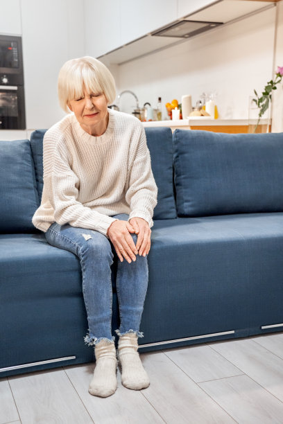 一位膝盖疼痛的老妇人坐在沙发上图片下载