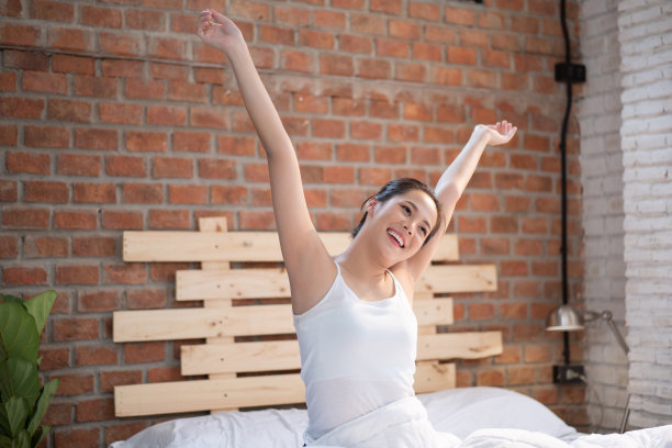 她躺在床上，早上醒来。她感到神清气爽。图片下载