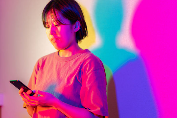 用智能手机在霓虹灯下点亮的年轻女子肖像图片下载