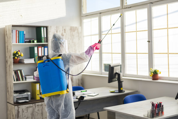 卫生工作者，一名穿着防护服的妇女正在为办公室消毒图片下载