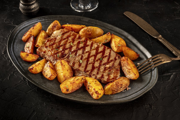 烤牛排与烤土豆角，在黑色的背景图片下载