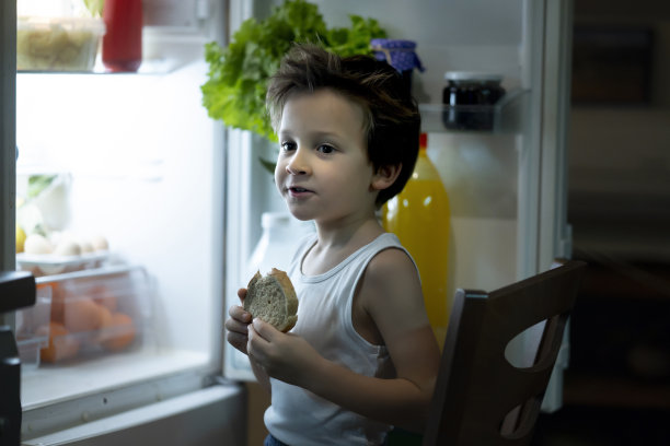 小男孩晚上在冰箱前图片下载