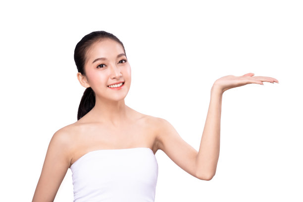 亚洲美丽的年轻女子的肖像指向一只手与手指上面的微笑的脸。在摄影棚里做美容广告和展示的女孩站在镜头前。图片下载