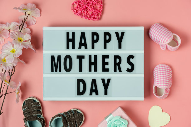 俯视图航拍图片装饰快乐母亲节文字节日背景概念。平板lay礼盒婴儿鞋和爱形状花上现代美丽的粉红色纸。复制空间设计。图片下载