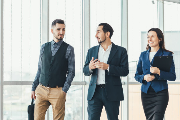 伙伴关系的概念。两个男人和女人一起走在办公室里，很高兴能在这样一个团队中工作。图片下载