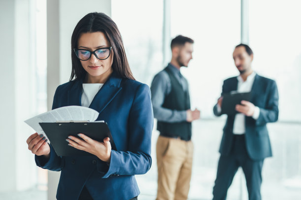 年轻的女助手站在最前线准备签署所有文件，而两名男子在后台进行谈判。图片下载