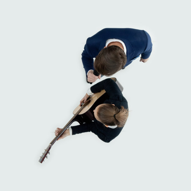 白人年轻女性吉他手舞蹈在白色背景穿着商务休闲装和持有原声吉他图片下载