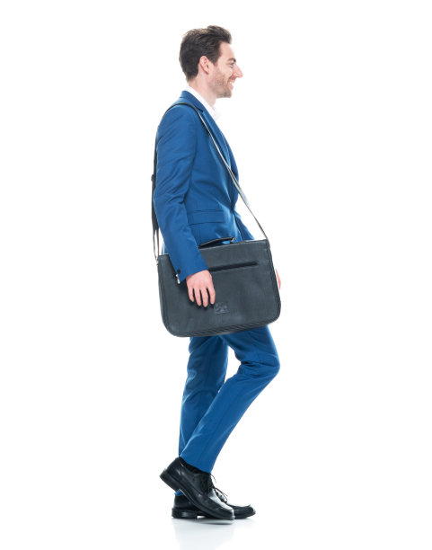 白人年轻男性商人走在前面的白色背景，穿着信使包和拿着包图片下载