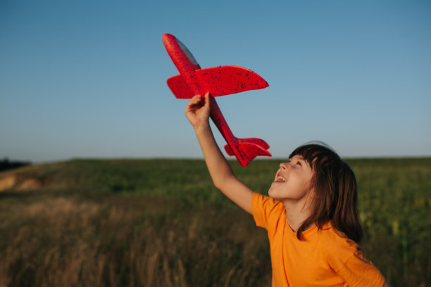 快乐的小女孩和泡沫飞机在绿色的田野里奔跑图片下载