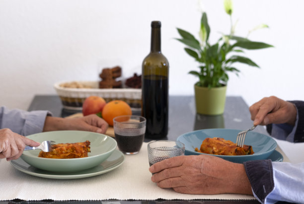 冠状病毒感染的居家观念。一对夫妇坐在桌前吃自制的意大利菜。馅料是蔬菜和肉酱的意大利面图片下载