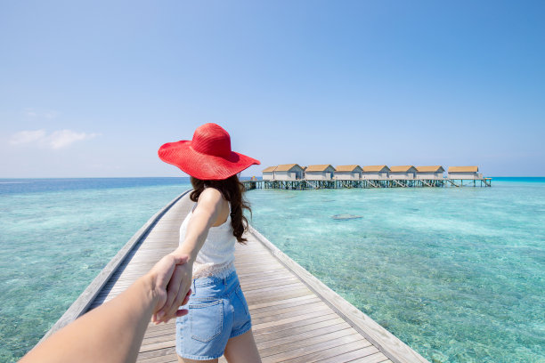 女人牵着男人的手或男朋友去海边看别墅度假，浪漫的马尔代夫海滩蜜月感觉如此放松和愉悦图片下载