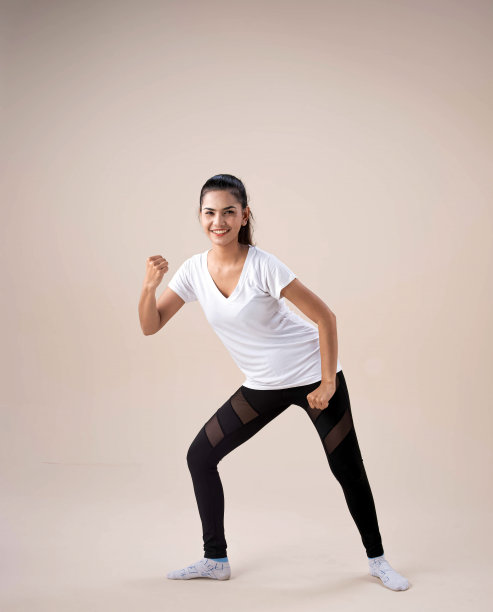 小姐双脚分开站立，稍微扭动一下，双手在身体旁边上下摆动，动来动去地进行舞蹈锻炼，有一种快乐的感觉图片下载