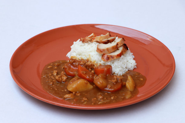 黄咖哩鸡或日本咖哩饭配橙黄色的圆菜，铺在白色地板上。图片下载