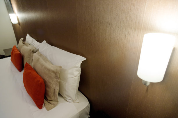 酒店的床上有红色的枕头和夜灯图片下载