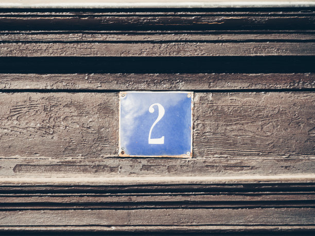 把两个门牌号贴在木墙上。图片下载