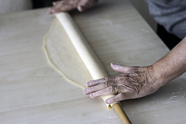 手用擀面杖在木桌上烘烤生面团图片下载