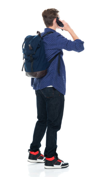 白人年轻男性穿着牛仔裤站在白色背景前，使用智能手机图片下载