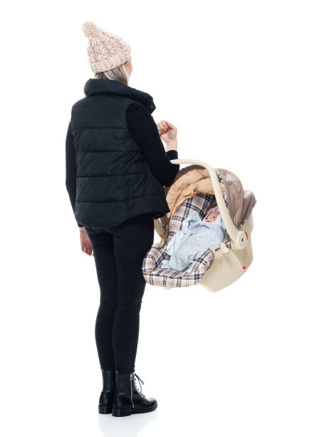 白种人婴儿-人类年龄无袖站在白色背景前，穿着暖和的衣服，抱着汽车安全座椅图片下载