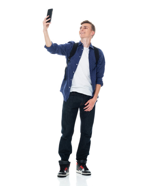 白人少年穿着牛仔裤站在白色背景前用手机拍照图片下载