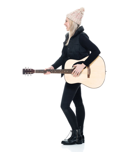 白人年轻女性吉他手站在白色背景穿着裤子和拿着吉他图片下载